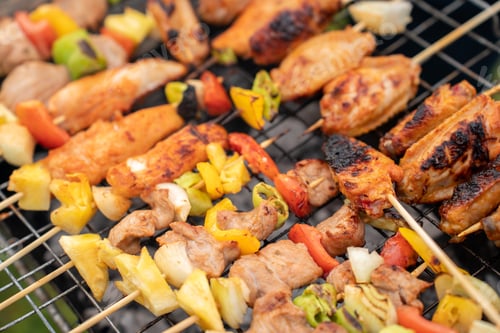 Vista previa: Assorted delicious grilled meat with vegetables on barbecue grill with smoke and flames.