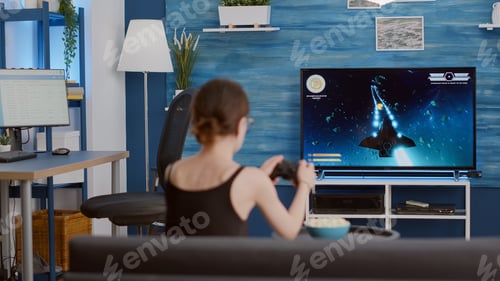 Preview: Gamer girl holding wireless controller playing console video game first person shooter on tv