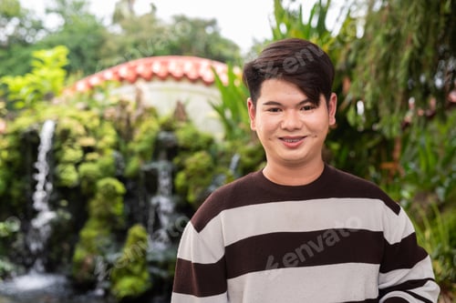 Preview: Young cute gay man in Zen style garden park with waterfall relaxing