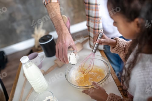 Preview: Father adding flour while daughter whipping eggs for pie