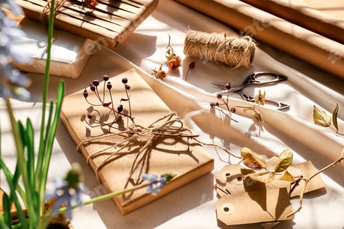 Preview: Gifts wrapped in recycled paper and decorated with dried flowers on linen tablecloth.