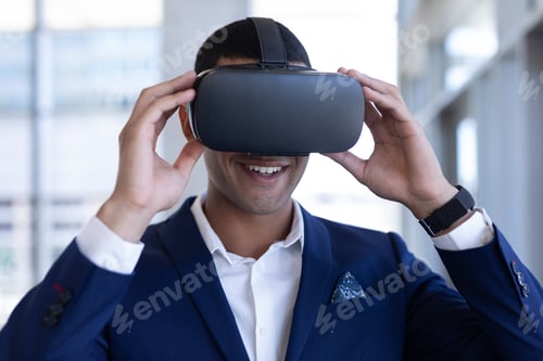 Preview: Happy young mixed-race businessman using virtual reality headset standing in modern office.