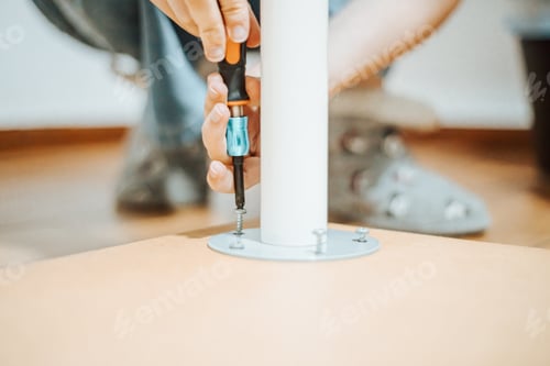 Preview: Woman hand using a screwdriver over furniture with copy space. Moving home concept