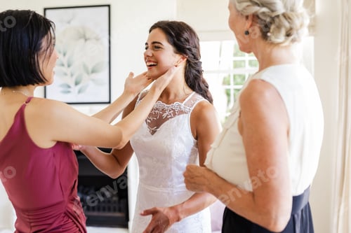 Preview: Bride in white dress smiling with friends adjusting her hair at home