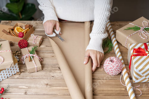 Preview: Woman s hands wrapping Christmas gift, close up. Unprepared presents on wooden background with decor