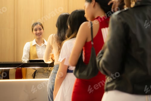 Preview: Young asian woman standing in line to buy movie tickets and in hand popcorn and drink,
