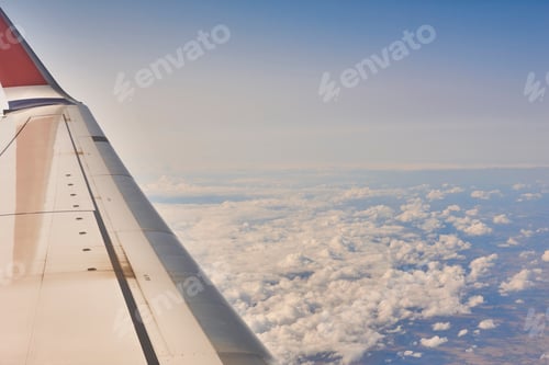 Preview: Aeroplane wing over a cloudy blue sky background. Flying