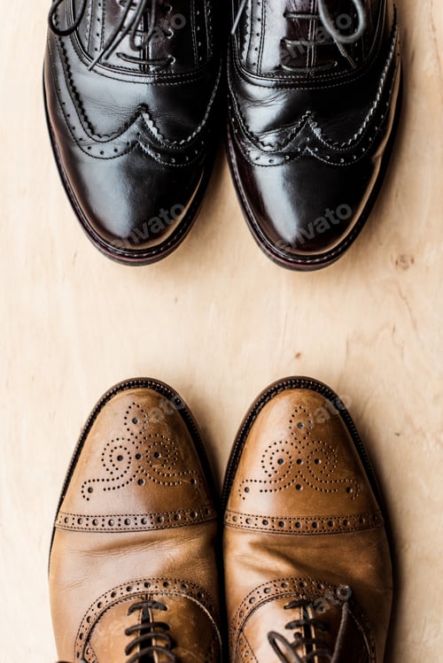 Preview: top view of black and brown pairs of leather shoes on wooden floor