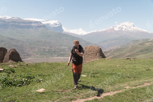 Preview: Traveler shooting video blog using smartphone in mountains