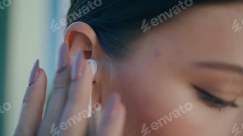 Preview: Woman face wireless earbud in ear close up. Portrait girl wearing modern headset