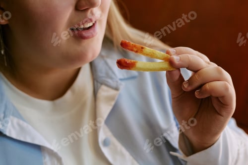 Preview: Young Woman Holding French Fries with Ketchup near Mouth Smiling