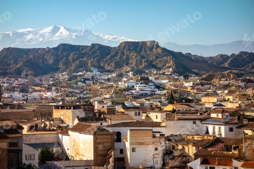 Preview: Scenic view of cave houses and snow-covered Sierra Nevada mountains in Guadix, Spain