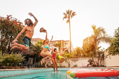 Preview: Group happy friends jumping in pool at sunset time
