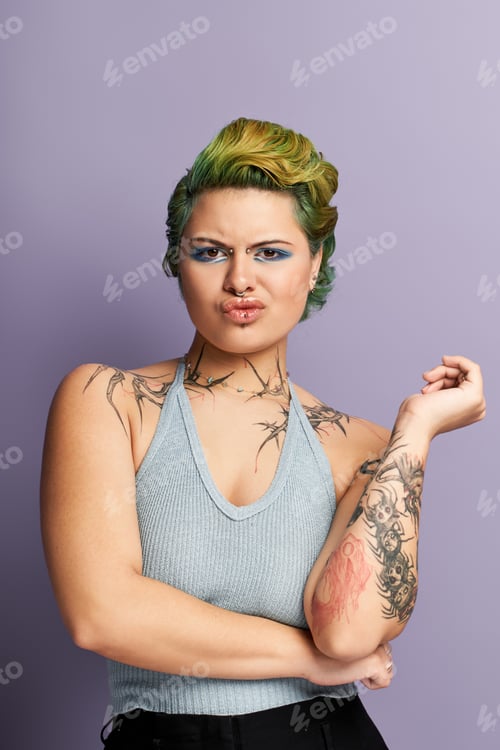 Preview: Vibrant young woman showcasing stylish fashion and artful body ink in a playful pose indoors