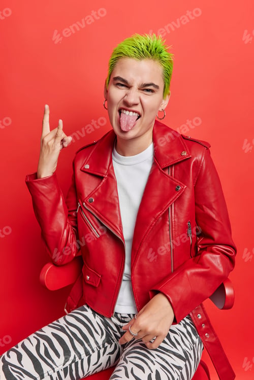 Preview: Sassy punk girl sticks out tongue shows heavy metal sign gesture feels cool has trendy green hairsty