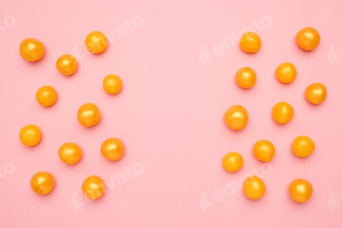 Vista previa: Sweet yellow candies with copyspace on a pink background, round sweet food