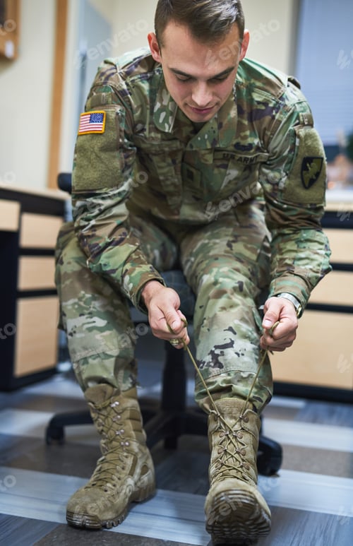 Preview: Shot of a young soldier tying his boot shoelaces in the dorms of a military academy