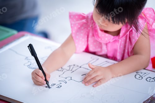 Preview: Selective focus at child hand holding magic pen. Asian cute girl doing art on white paper.