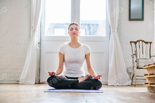 Preview: Young woman practicing yoga lotus position in apartment