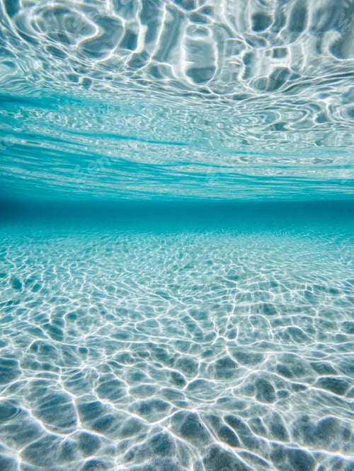 Preview: View of clear turquoise water with sunlight creating ripples on the sandy bottom.