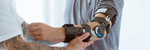 Preview: Tattooed physiotherapist who puts an orthosis on the hand of a young patient after an accident