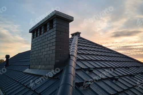 Preview: Chimney on house roof top covered with metallic shingles under construction.
