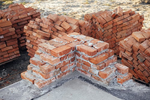 Preview: Bricks masonry with cement on concrete foundation close up. Building materials at construction site