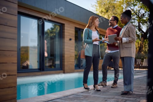 Preview: Happy black real estate agent talking to her client during open house day.