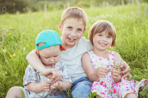 Preview: Happy kids hugging sitting on the green grass outside