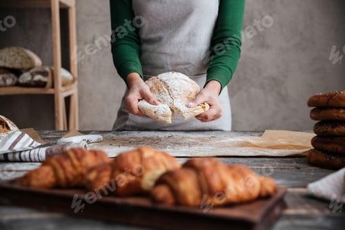Preview: Lady baker standing near croissants holding bread