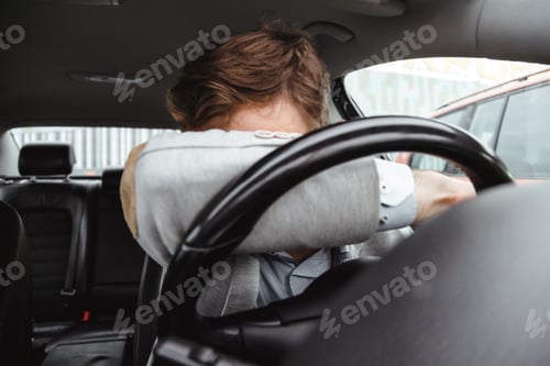 Preview: Exhausted driver resting on steering wheel