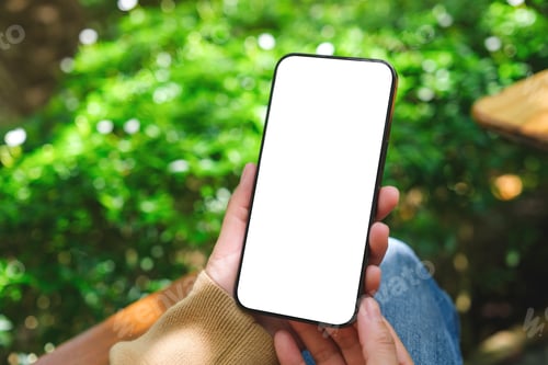 Preview: Mockup image of a woman holding mobile phone with blank white desktop screen in the outdoors