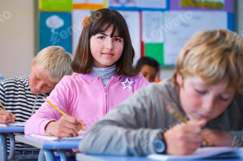 Preview: Portrait of girl in classroom, sitting at desk, doing classwork
