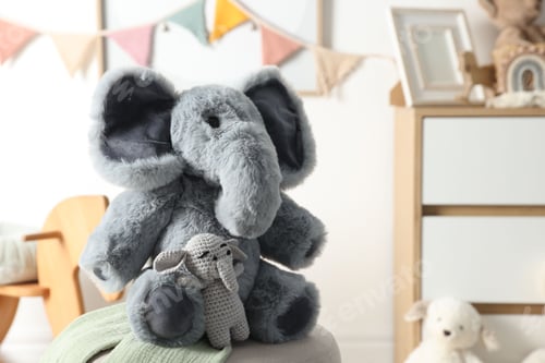 Preview: Cute soft toy elephants on pouf in child's room, closeup. Space for text