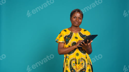 Preview: Smiling happy person checking internet websites on her tablet in studio