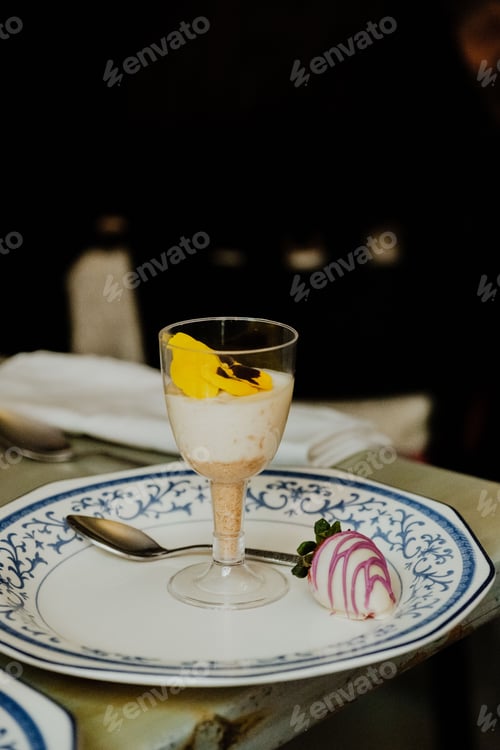Preview: White plate with a dessert with a strawberry arranged around a silver spoon