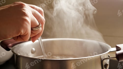 Preview: Female hand stirring boiling soup in pot. Healthy nutrition, cooking at home, hot steam.