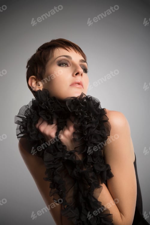 Preview: Studio portrait of woman wearing and holding onto black boa ruffle
