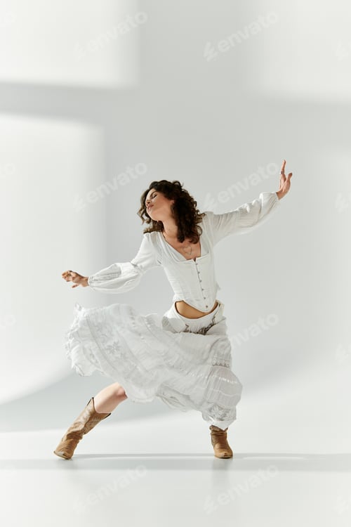 Preview: Young woman expresses joy in a stylish white outfit while dancing in a bright studio space