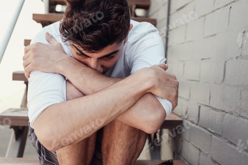 Preview: Depressed young adult man sitting alone, mental health concept