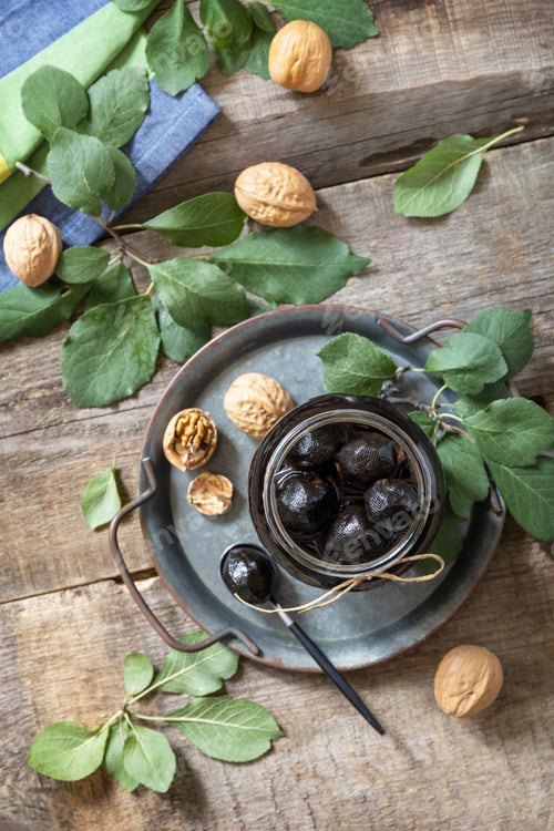 Preview: Handmade jam made from green fresh walnuts on a wooden background.