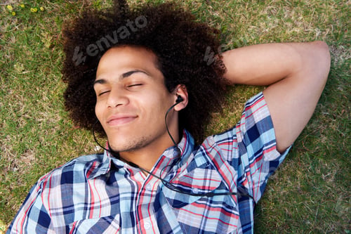 Preview: young man lying down on grass listening to music