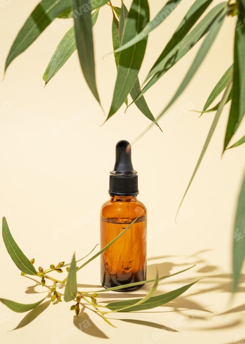 Preview: Face and body serum in bottle on a yellow background with green leaves and shadow.