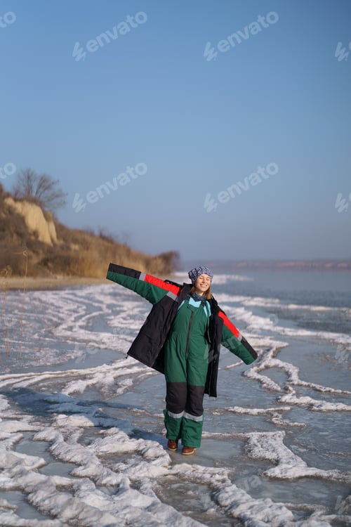 Preview: Woman enjoying winter while standing on frozen lake. Freedom