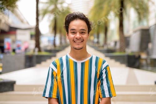 Preview: Portrait of handsome multi-ethnic young man wearing colorful shirt outdoors during summer and