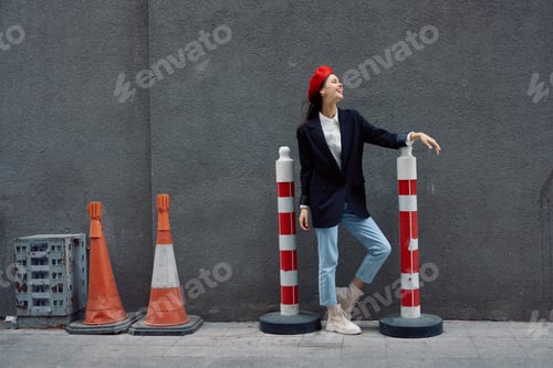 Preview: Fashion woman standing leaning against a wall street against a background of the city road works