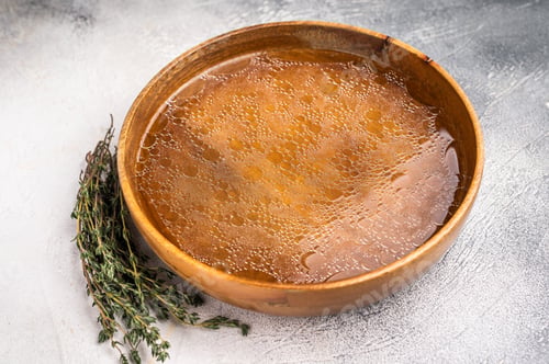 Preview: Chicken Bouillon or Broth in a wooden plate. white background. top view
