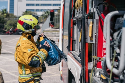 Preview: Firefighter picking up equipment bag from firetruck at fire station