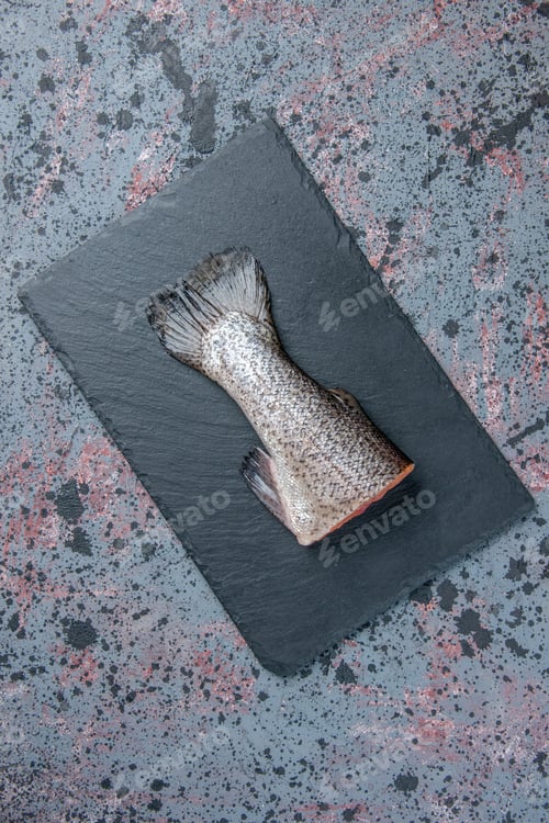 Preview: Above view of fresh raw fish on dark color tray on blue black mix colors background with free space