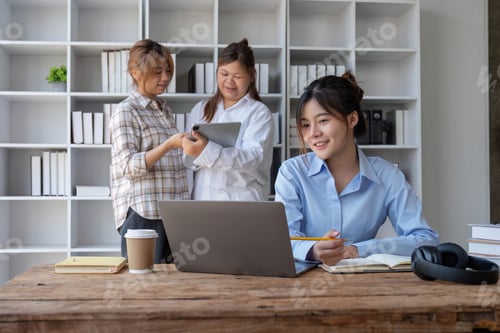 Preview: College students using laptop while sitting at table. Group study for school assignment.